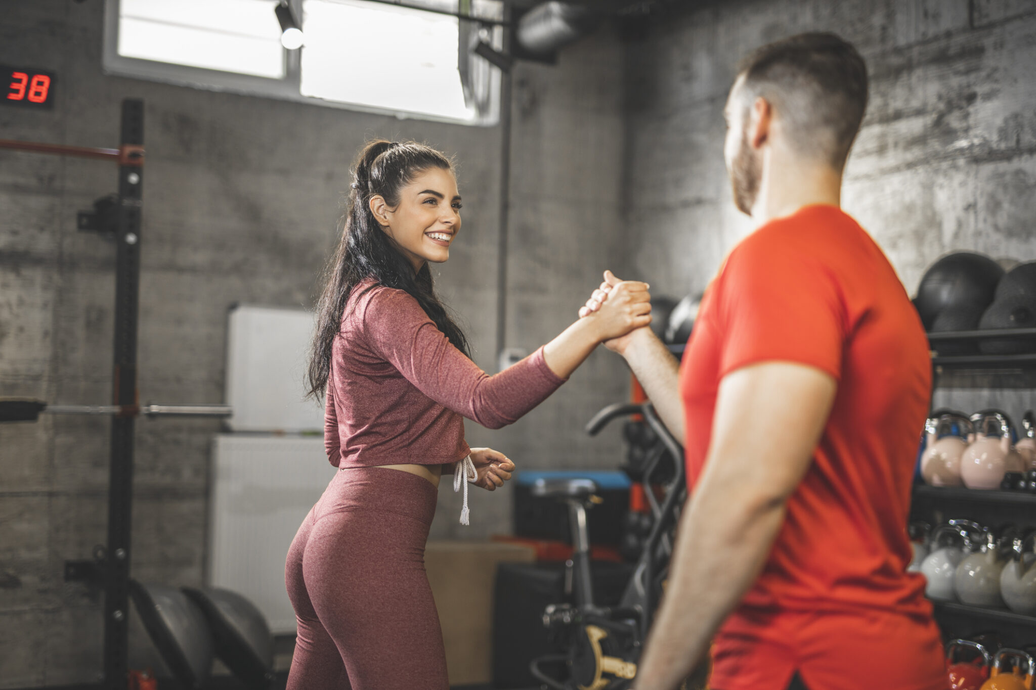 Young woman and man are shaking hands after an intense training in the gym.