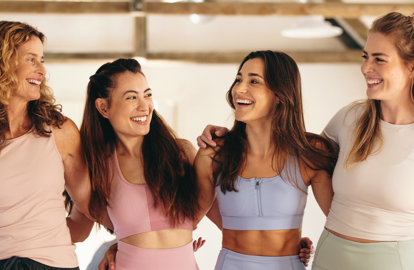 A group of ladies in gym wear smiling in a studio.